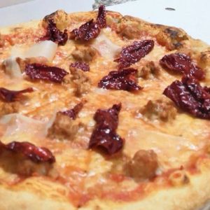Pizza con salsiccia, peperoni cruschi e scaglie di formaggio