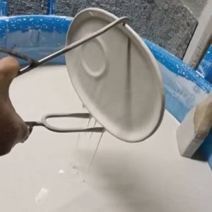 Un piatto immerso nello smalto bianco con una pinza