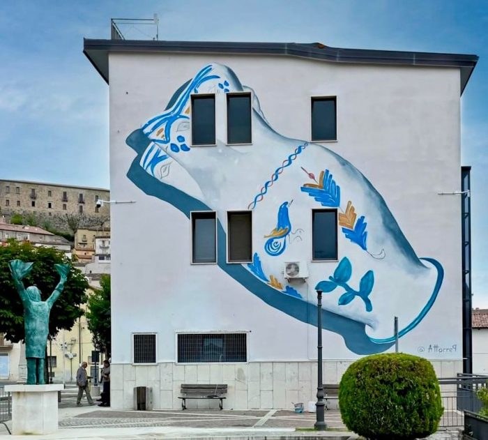Murale con una grande brocca bianca decorata con l’uccellino blu, dipinta sulla facciata laterale del Municipio