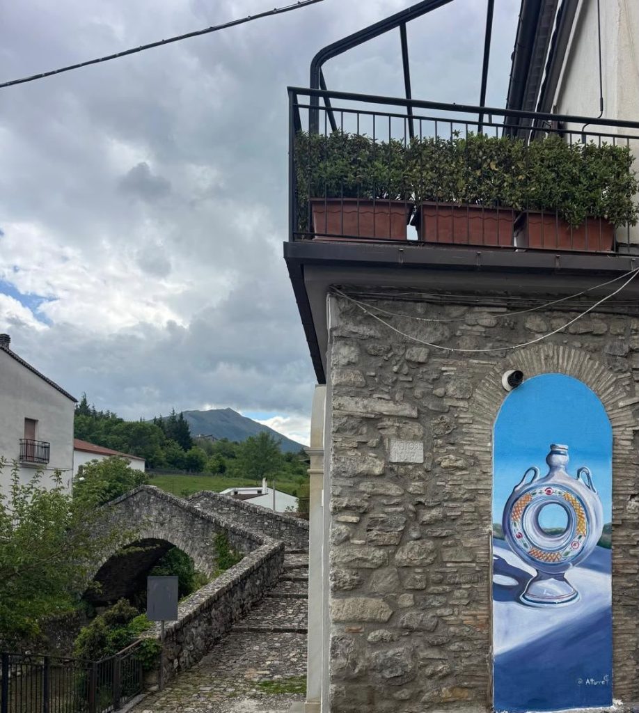 Vaso ad anello dipinto dentro un arco di pietra, accanto al vecchio ponte